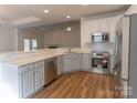 Modern kitchen featuring stainless steel appliances, white cabinets, quartz countertops, and wood-look flooring at 212 Mary Caroline Springs Dr, Mount Holly, NC 28120