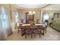 Charming dining area with a wooden table set for eight, complemented by a decorative chandelier and large windows at 514 Galesburg Dr, Monroe, NC 28110