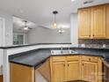 Bright kitchen with stainless steel sink, wood cabinetry, and black countertops at 6792 Mallard Park Dr, Charlotte, NC 28262
