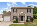 Classic two-story home featuring neutral siding, an attached garage, and landscaped front yard at 8309 Knapp Ct, Locust, NC 28097
