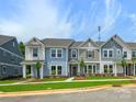 A view of several two-story townhomes with coordinated exteriors, lush lawns, and well-kept landscaping at 10113 Mamillion Dr, Huntersville, NC 28078