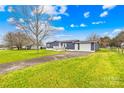 Well-maintained blue home features a green lawn, an attached garage, and ample parking on a sunny day at 133 Hallmark Estates Dr, Statesville, NC 28625