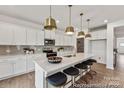 Bright kitchen featuring a large island, stainless steel appliances, white cabinetry, decorative lighting and hardwood flooring at 273 Batten Ridge Dr # 285, Statesville, NC 28677