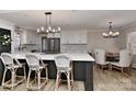 Bright kitchen with white cabinets, a large center island, and an adjacent dining area with stylish lighting at 9414 Machado Dr, Indian Trail, NC 28079