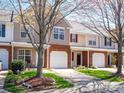 View of townhomes, showcasing individual garages, brick and siding, and attractive landscaping at 11907 Maria Ester Ct, Charlotte, NC 28277