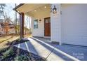 Inviting front porch with dark wood door, side lights, and manicured landscaping at 268 Lytton Farm Rd, Troutman, NC 28166