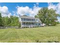 Two-story home boasts a covered porch, spacious lawn, mature trees, and a white fence for added curb appeal on a sunny day at 3929 Wexford Ln, Denver, NC 28037
