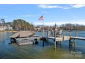 Lakeside dock featuring a boat lift and an outdoor dining area perfect for enjoying the water at 122 N Longfellow Ln, Mooresville, NC 28117