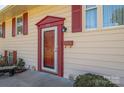 Charming front door with red trim, house number, and red shutters on a light yellow home at 1501 Fern Forest Dr, Gastonia, NC 28054