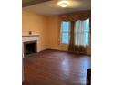 A living room features wood floor, a fireplace and a window with curtains at 201 N Crawford St, Monroe, NC 28112