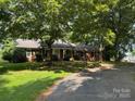 Charming brick home with lush trees, a curved driveway, and a welcoming front porch at 4210 Wrangler Sw Dr, Concord, NC 28027