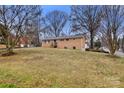 View of brick home exterior with spacious lawn and mature trees at 7047 Cheyenne Dr, Charlotte, NC 28262