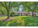 Well-maintained white house with a green lawn and mature trees on a sunny day at 7613 Whistlestop Rd, Charlotte, NC 28210