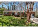 Charming single-story brick home with a lush green lawn and trees, featuring a cozy front porch at 8101 Kerrybrook Cir, Charlotte, NC 28214