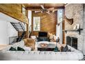 Spacious living room with exposed wood walls, a fireplace, and open staircase at 11101 Winding Way Rd, Charlotte, NC 28226