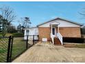 Fenced backyard with a brick and white house, featuring a concrete patio at 114 Eller Rd, Gastonia, NC 28056