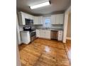 Modern kitchen with stainless steel appliances, white cabinets and tiled backsplash, and wood flooring at 120 3Rd Ave, Conover, NC 28613
