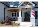 Charming covered front porch with comfortable seating, wood ceiling, and stylish black double doors at 129 Ryleigh Dan Pl, Mooresville, NC 28115