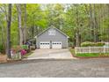 Detached two-car garage with white doors and siding, accented by a white fence and spring blooms at 140 Rustic Way Ln, Mooresville, NC 28117