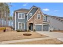 Charming two-story home featuring a mix of stone and gray siding, plus an attached two-car garage at 155 Autumnwood Rd, Troutman, NC 28166