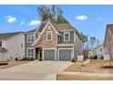 Charming two-story home featuring a mix of stone and gray siding, plus an attached two-car garage at 155 Autumnwood Rd, Troutman, NC 28166