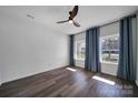 Serene bedroom with hardwood floors, two windows, a ceiling fan, and blue curtains at 15603 Pine Glen Ct, Charlotte, NC 28273