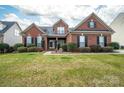 Inviting brick home with a lush green lawn and mature landscaping under a partly cloudy sky at 2555 Holly Oak Ln, Gastonia, NC 28056