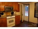 Kitchen featuring white appliances, wood cabinets, and access to the backyard through a door at 522 Perry St, Troy, NC 27371