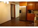 Well-lit kitchen featuring stainless steel refrigerator, wood cabinets, and wood flooring at 522 Perry St, Troy, NC 27371