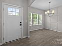 Inviting entryway showcasing a white front door, natural light, and modern light fixtures in the adjacent room at 531 Harlech Ct, Fort Mill, SC 29715