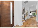 Home foyer with a modern wood door, wood staircase, and wood flooring, creating a warm inviting space at 5610 Farmbrook Dr, Charlotte, NC 28210