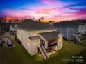 Rear view of a home with a screened in porch with stairs leading to a backyard under a colorful sunset sky at 6022 Candlestick Ln, Lancaster, SC 29720