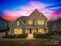 Charming two-story home boasts stone and siding exterior, manicured lawn, and inviting curb appeal under a vibrant sunset at 6022 Candlestick Ln, Lancaster, SC 29720