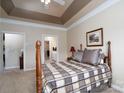Inviting main bedroom with a beautiful tray ceiling, a wooden bed frame, and an ensuite bathroom at 8568 Windsor Ridge Dr, Charlotte, NC 28277