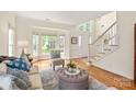 Bright living room with large windows, a staircase, and stylish furniture arranged on a patterned rug at 1006 Baldwin Ln, Waxhaw, NC 28173
