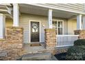 Welcoming front porch with stone pillars, a decorative wreath, and a cozy entrance at 11013 Dundarrach Ln, Charlotte, NC 28277