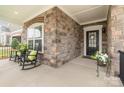 Inviting front porch with rocking chairs, brick facade, and decorative floral arrangements flanking the black front door at 15103 Honeycutt Dr, Huntersville, NC 28078