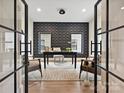Inviting home office with patterned wallpaper, two windows, an area rug, and black framed glass doors at 1516 N Caldwell St, Charlotte, NC 28206