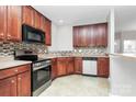 Well-equipped kitchen boasts wooden cabinets, tile backsplash, and a full suite of modern appliances at 2313 Calabassas Ln, Matthews, NC 28105