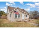 Angle view of a quaint home with a front porch, American flag, and neat landscaping under a bright sky at 306 W 2Nd St, Cherryville, NC 28021