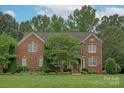 Charming two-story brick home with a well-manicured lawn and mature landscaping at 409 Running Horse Ln, Waxhaw, NC 28173