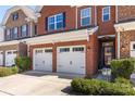 Close-up of a brick townhome showcasing a two-car garage, a garden area, and a glass front door at 107 Dellbrook St # B, Mooresville, NC 28117