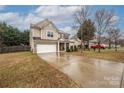 Two story home with attached garage, neutral siding, a well-manicured lawn, and a paved driveway in a suburban neighborhood at 128 Lacona Trce, Mooresville, NC 28115
