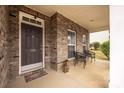 Inviting front porch features brick accents, an elegant entry door, and a cozy seating area for relaxing outdoors at 128 Lacona Trce, Mooresville, NC 28115
