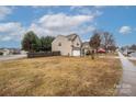 A view of the side yard of a two-story home with a manicured lawn and established trees in a suburban neighborhood at 128 Lacona Trce, Mooresville, NC 28115