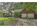 Side view of a brick home featuring an attached two-car garage, driveway, and beautiful landscaping at 12606 Bradford Hill Ln, Huntersville, NC 28078
