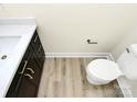 Compact bathroom featuring a sleek vanity, toilet, and modern fixtures complemented by light wood-look flooring at 1508 Oak St, Charlotte, NC 28269