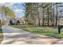 Spacious property featuring a long driveway, a well-manicured lawn, and a charming two-story home nestled among tall trees at 125 Cherokee Dr, Mooresville, NC 28117