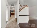 Interior hallway with neutral tile flooring, wooden staircase, and sightlines to the kitchen at 200 W 18Th St, Newton, NC 28658