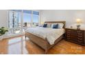 Bedroom with hardwood floors, a large window with city views, and a wooden dresser at 230 S Tryon St # 1111, Charlotte, NC 28202